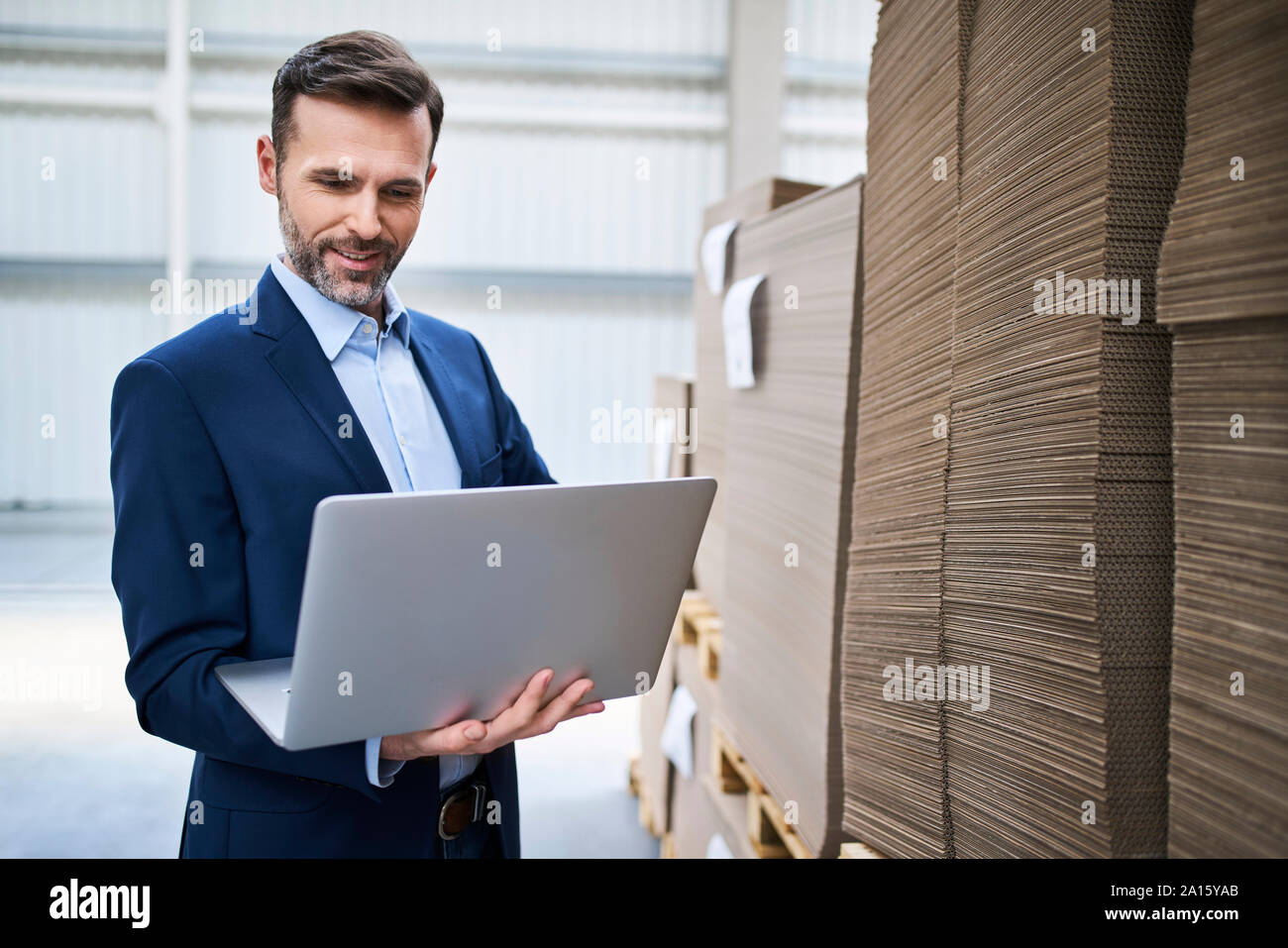 Uomo d affari con computer portatile in un magazzino di fabbrica Foto Stock