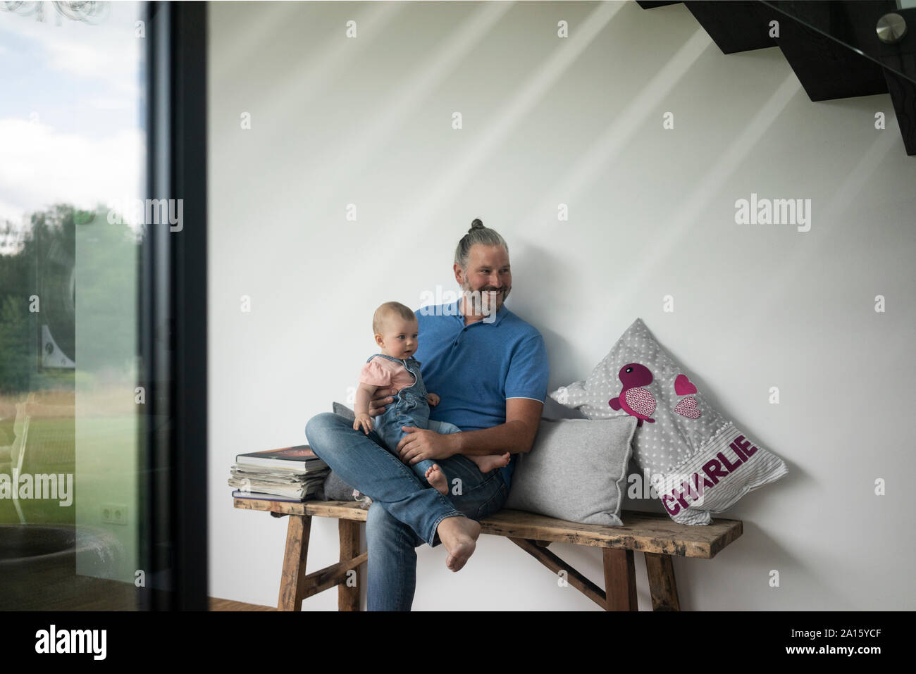 Felice coppia uomo seduto con baby girl su un banco di lavoro a casa Foto Stock