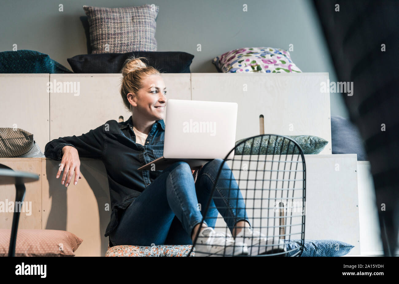 Sorridente casual imprenditrice utilizzando computer portatile in ufficio lounge Foto Stock