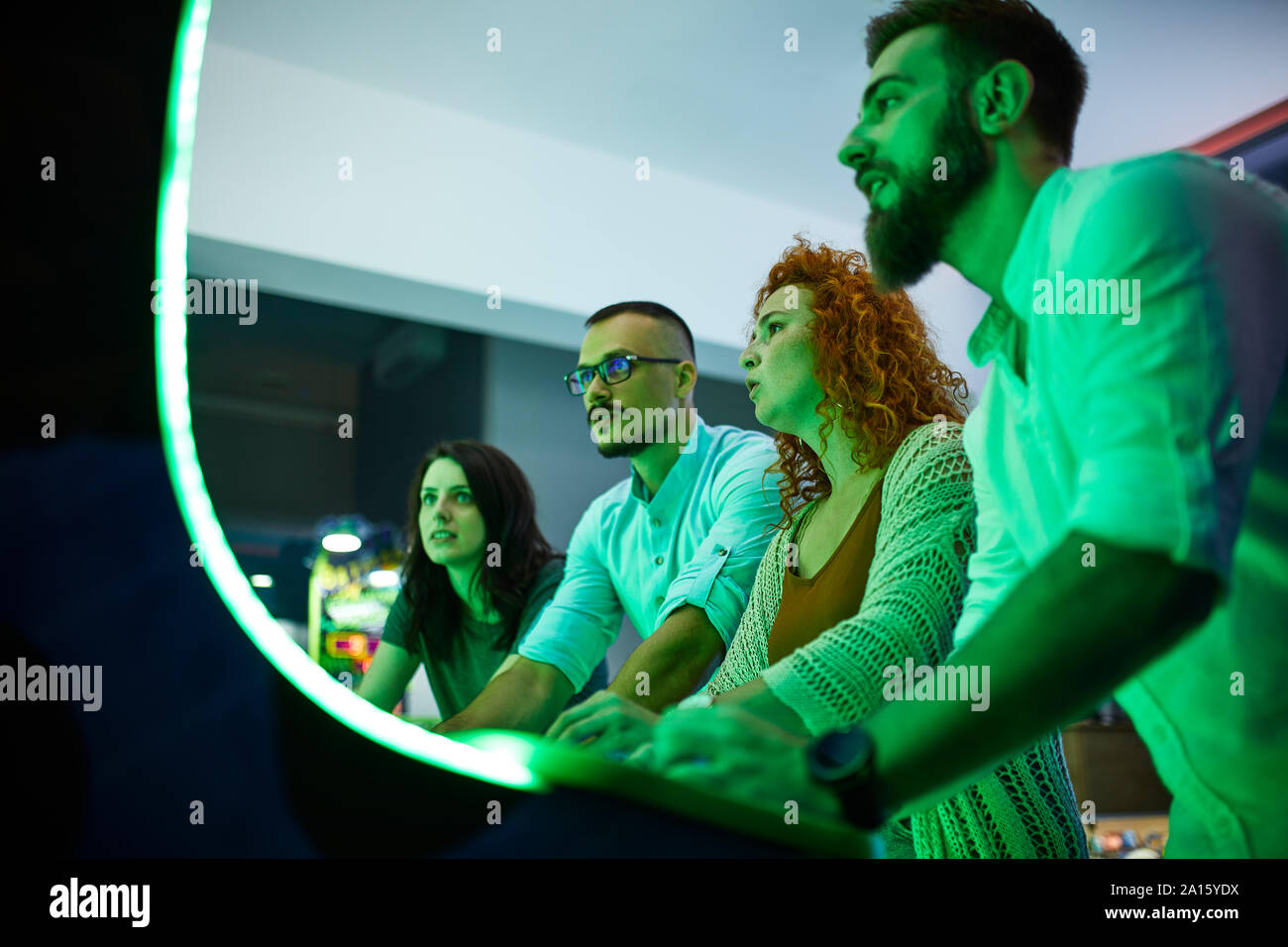 Concentrati gli amici a giocare con una macchina da gioco in un divertimento arcade Foto Stock