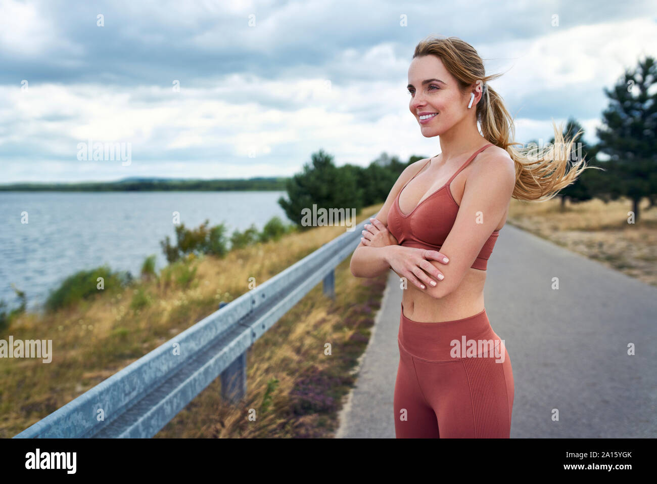 Athletic woman standing all aperto con bracci incrociati e guardando lontano Foto Stock