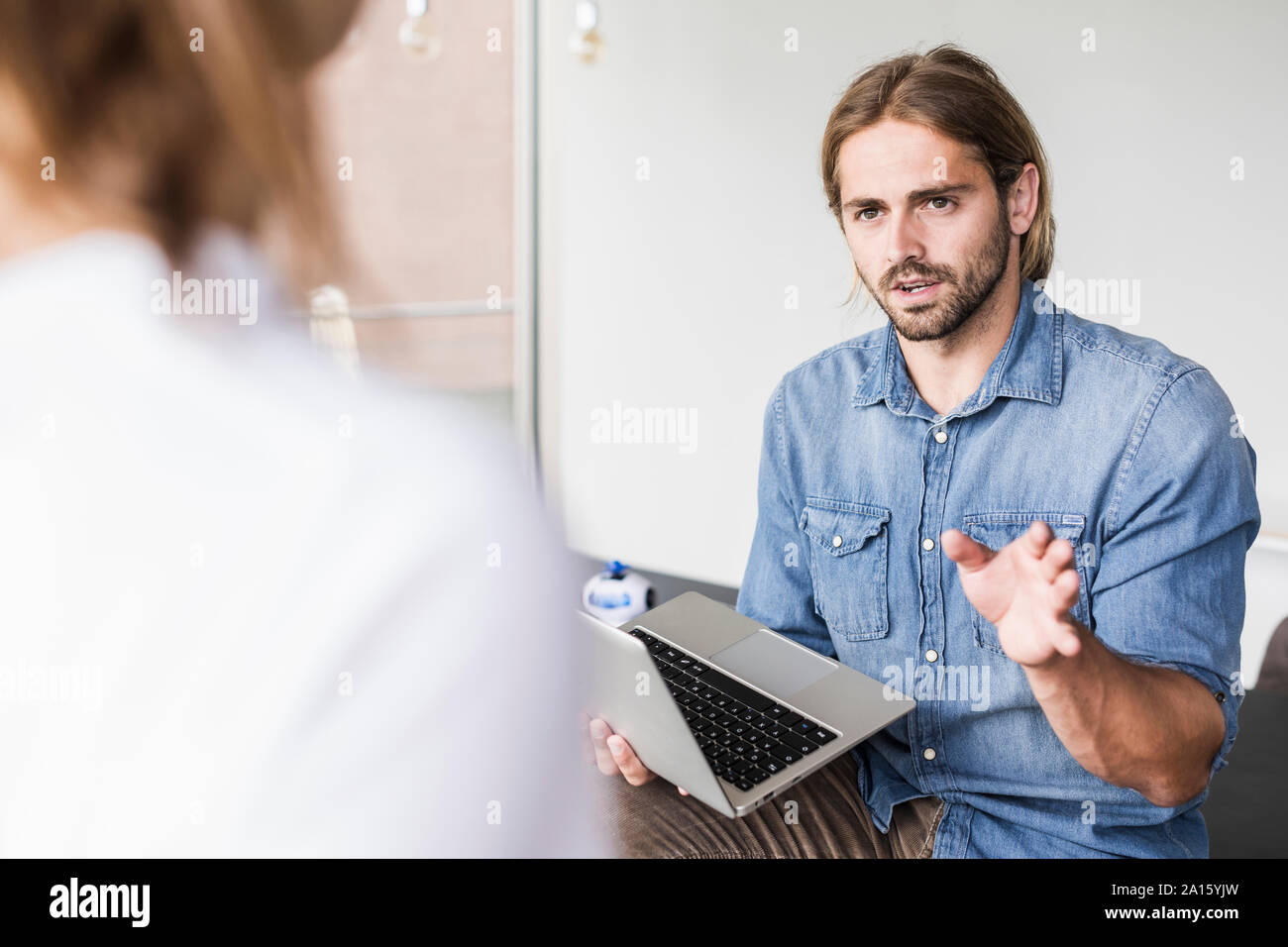 Giovane uomo d affari con computer portatile parlando di imprenditrice in office Foto Stock