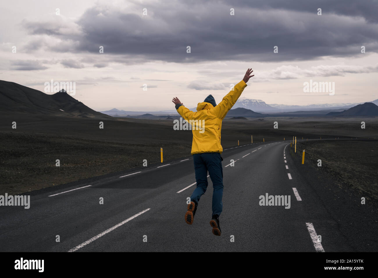 Uomo felice salti di gioia su una strada vuota, Islanda Foto Stock