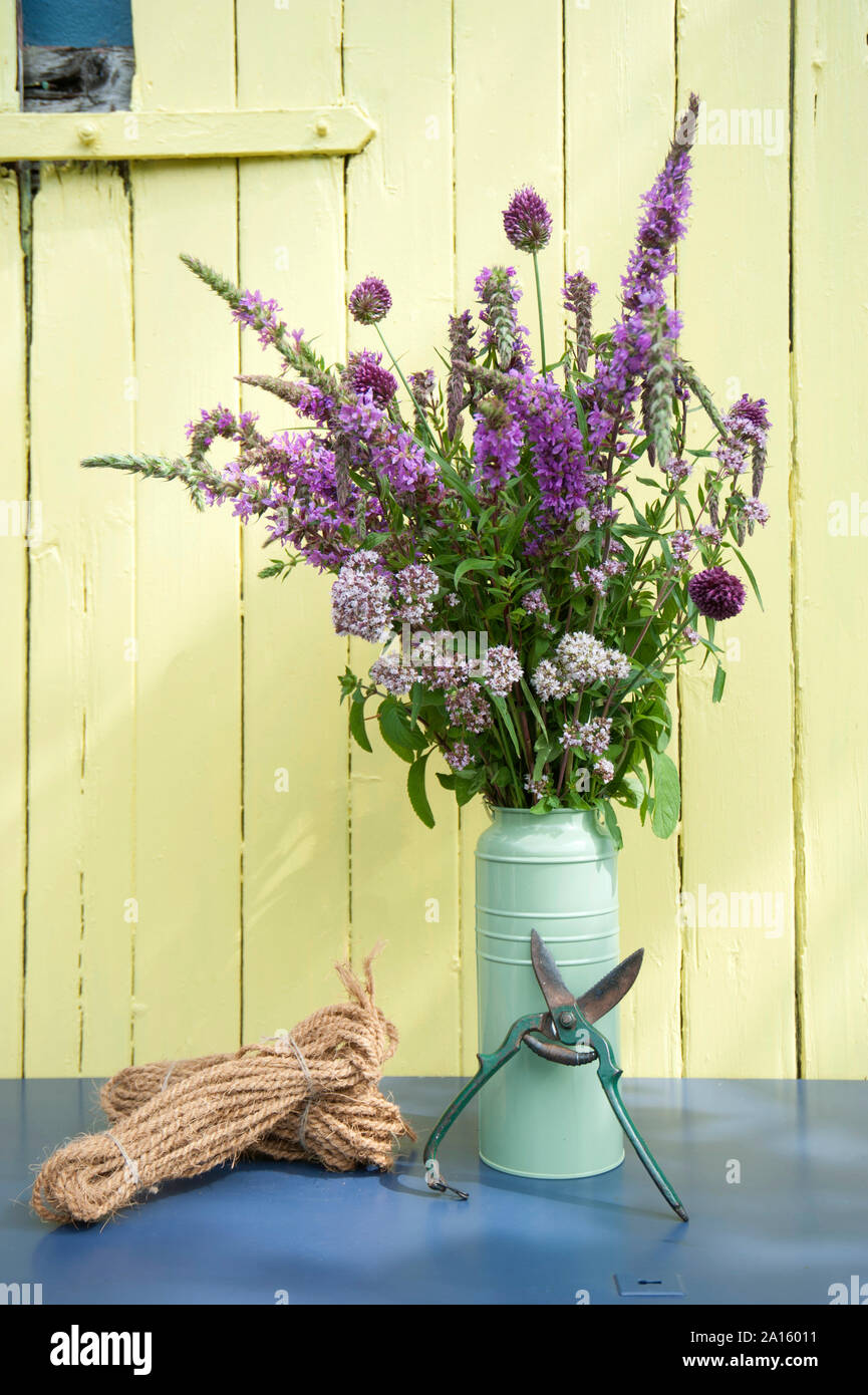 Estate decorazioni per la tavola, mazzo di fiori di erbe in vendemmia può con potatore e funi Foto Stock