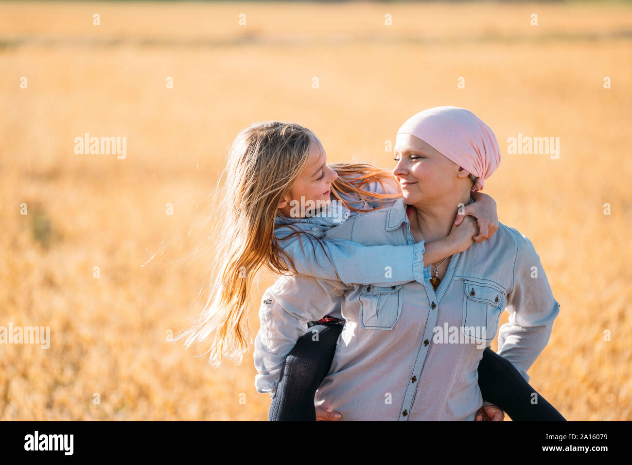 Una donna con il cancro che porta la figlia sulla sua schiena, faccia a faccia Foto Stock