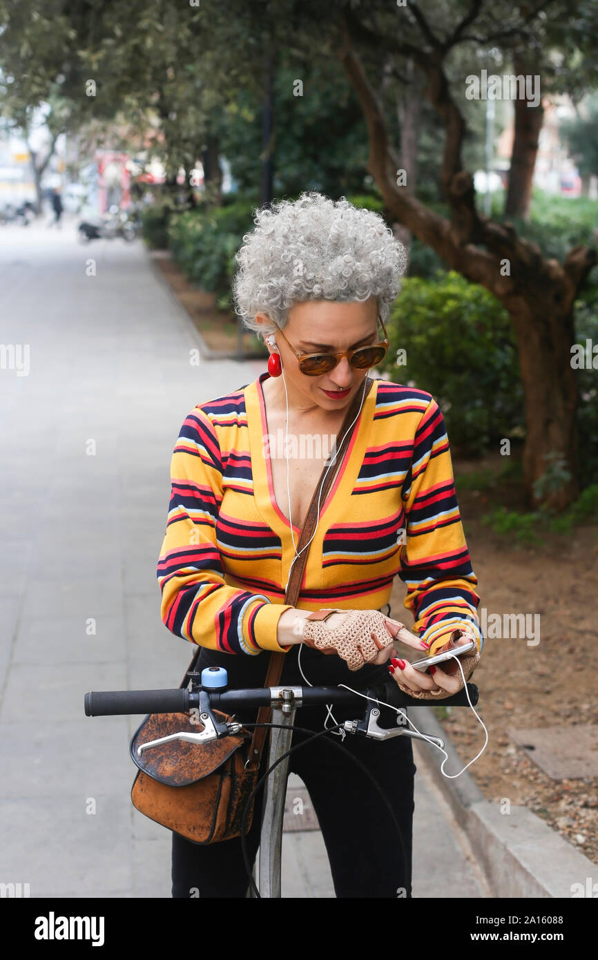 Donna matura con bicicletta utilizza lo smartphone Foto Stock