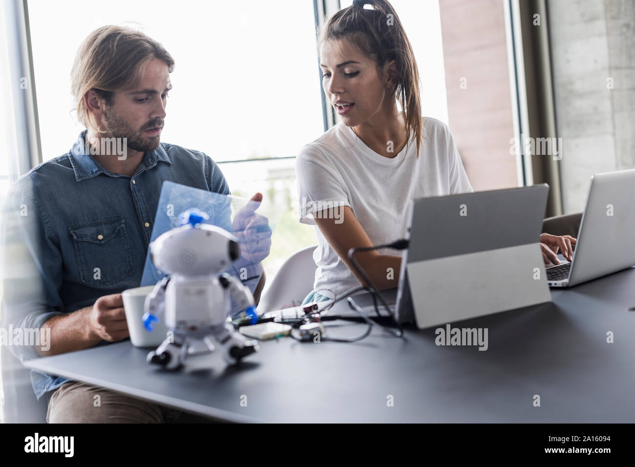 Giovane uomo e donna che lavorano insieme alla scrivania in ufficio Foto Stock