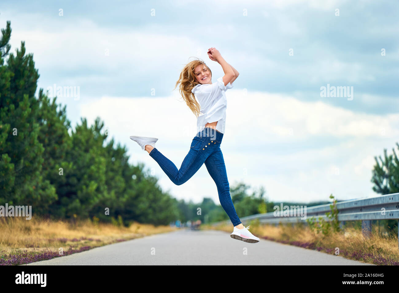 Donna allegra salto sulla strada rurale Foto Stock