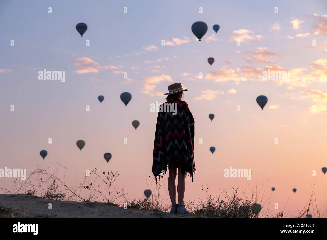 Giovane donna e i palloni ad aria calda di sera, Goreme, Cappadocia, Turchia Foto Stock