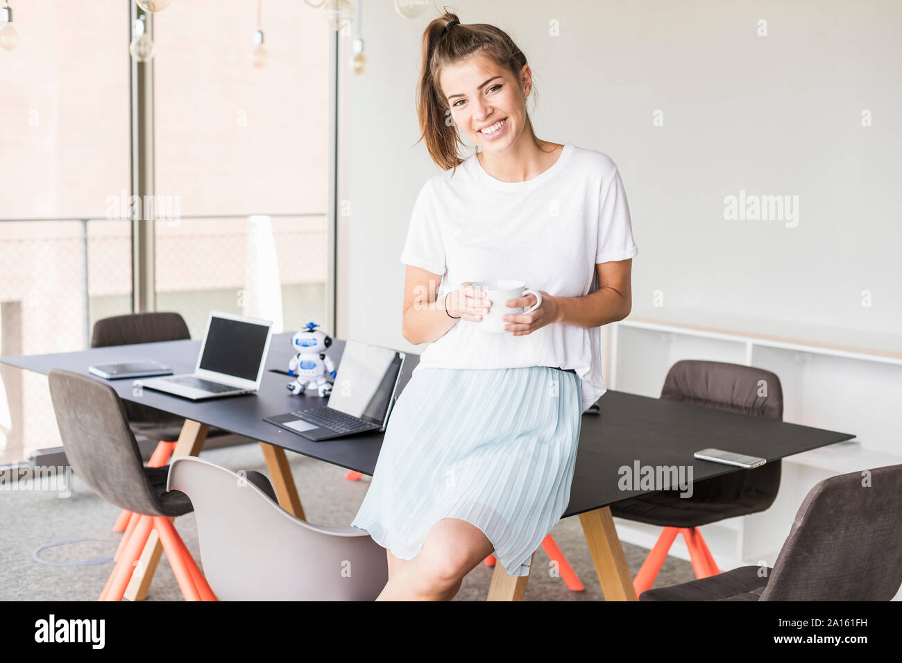Ritratto di giovane sorridente imprenditrice avente pausa caffè in ufficio Foto Stock