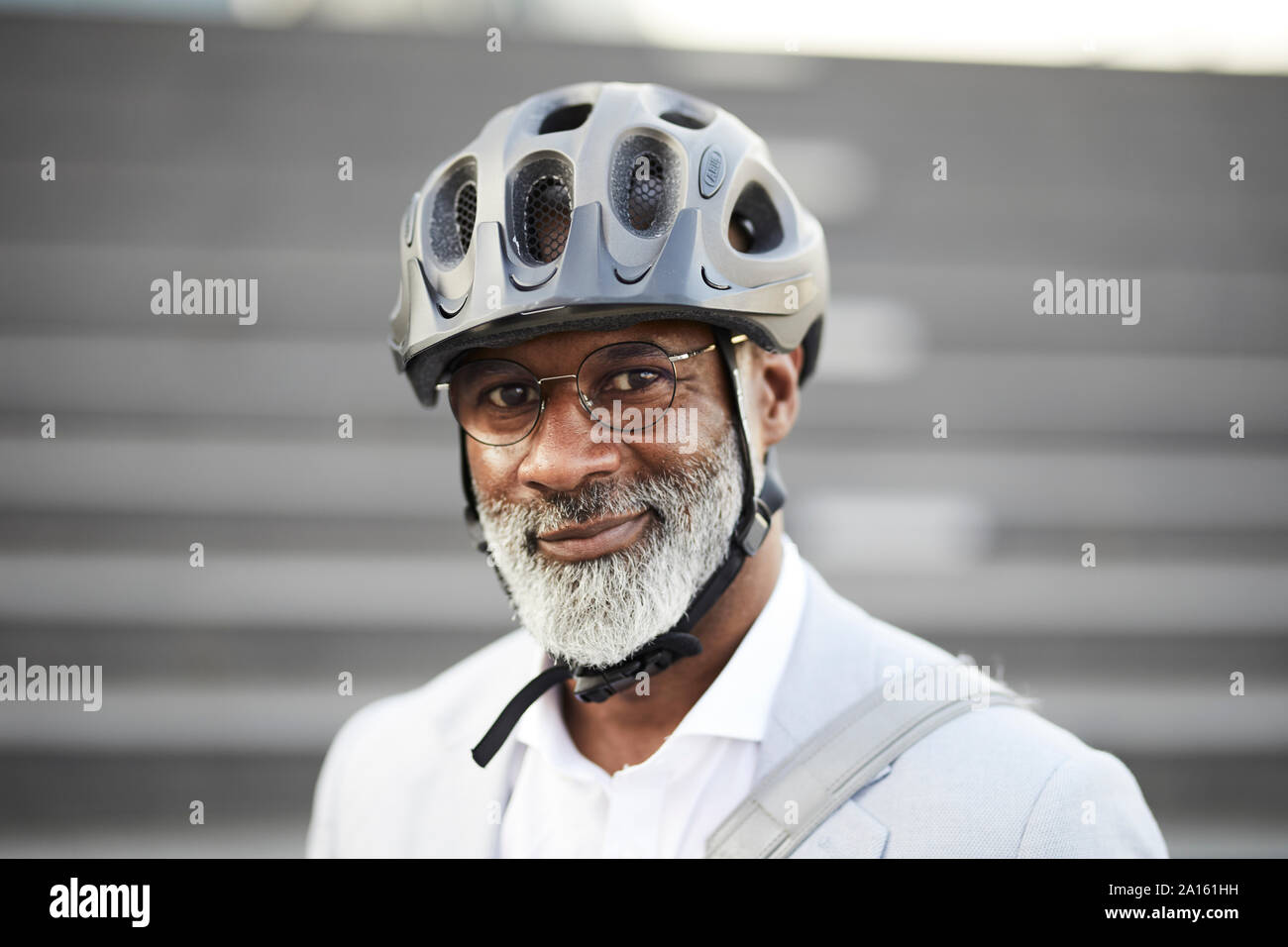 Ritratto di sorridente imprenditore maturo con barba grigia che indossa il ciclismo casco e occhiali di protezione Foto Stock