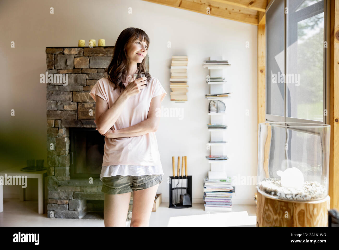 Donna sorridente di vetro di contenimento di acqua a casa Foto Stock