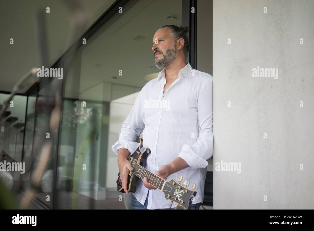 Uomo maturo tenendo la chitarra a casa Foto Stock