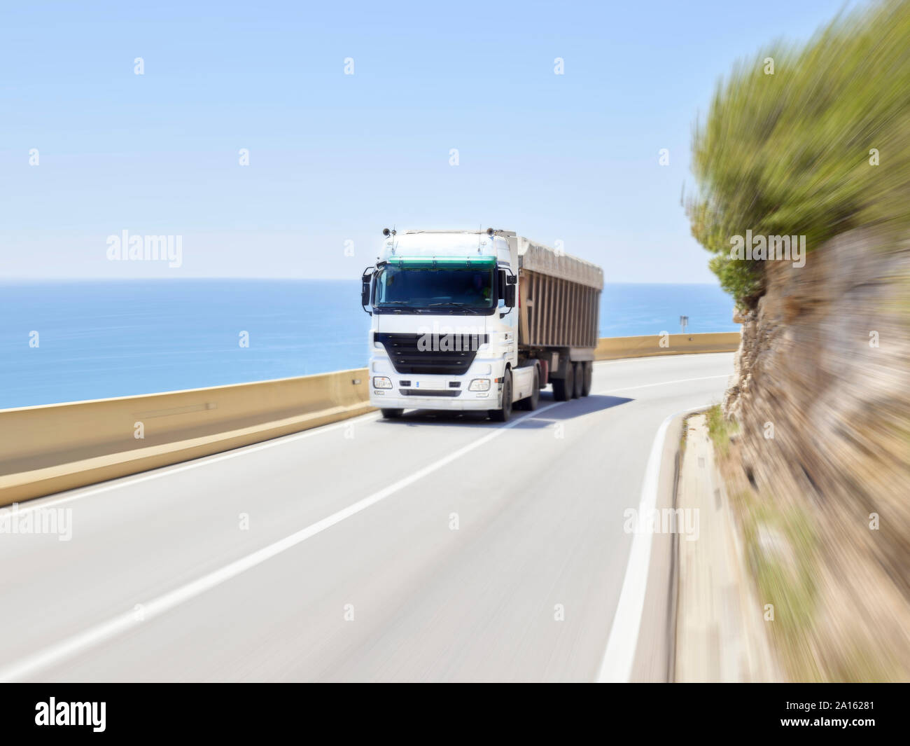 La guida di automezzi pesanti lungo la barriera di Jersey di autostrada costiera, Sitges, Barcelona, Spagna Foto Stock