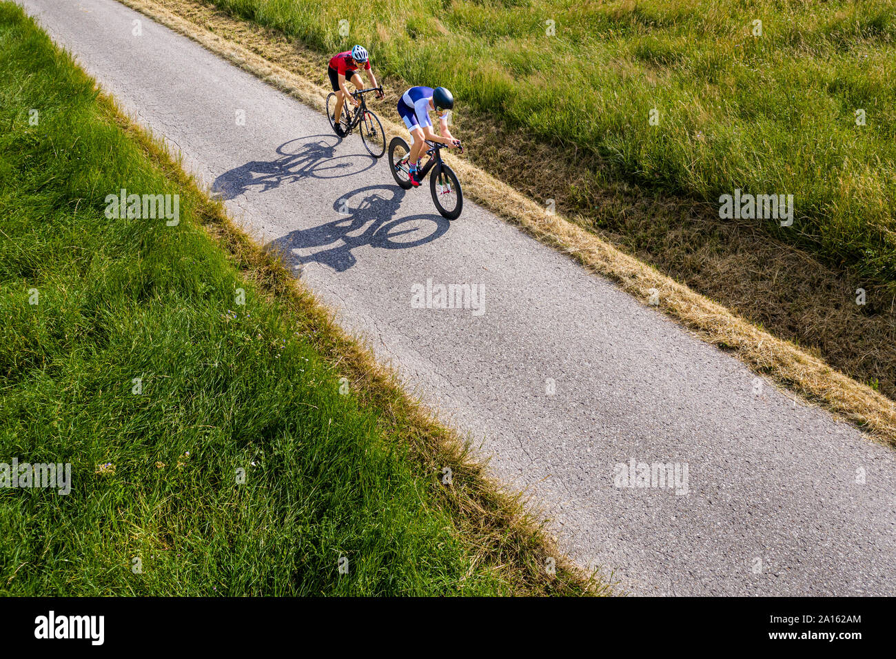 Triatleti equitazione bicicletta sulla strada di campagna, Germania Foto Stock