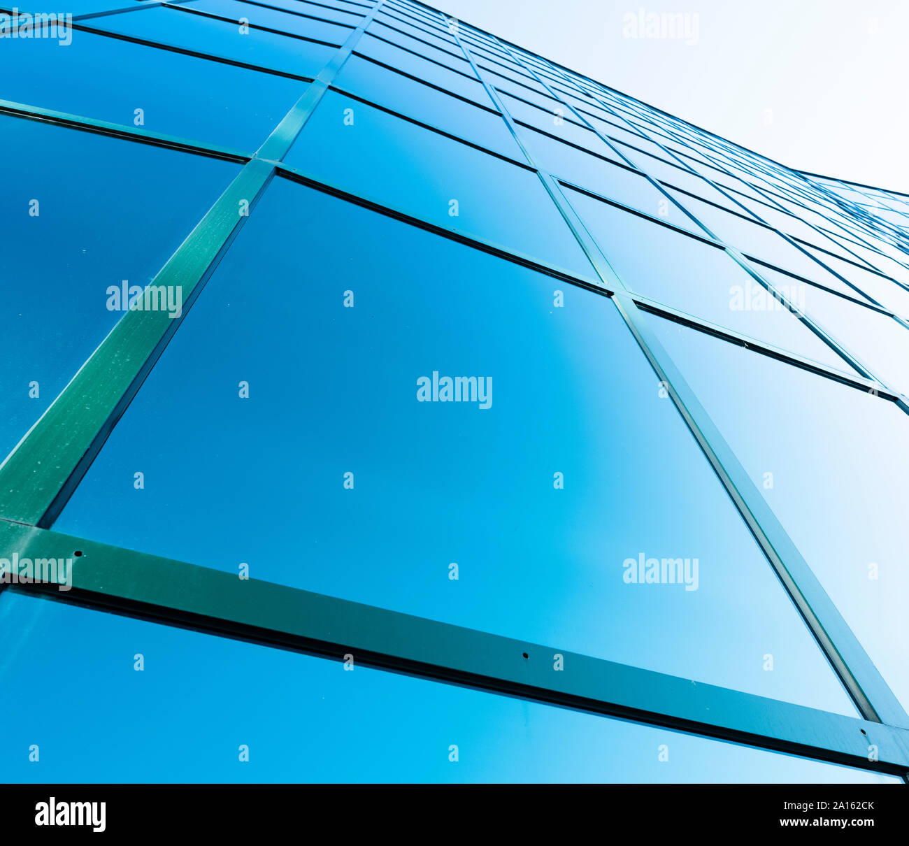 Facciata di un ufficio moderno edificio in vetro e acciaio con riflessi di cielo blu Foto Stock