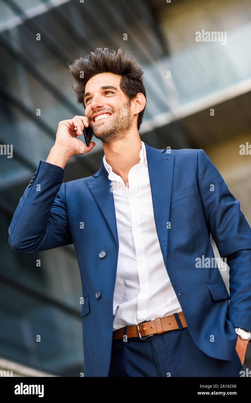 Happy businessman parlando al cellulare al di fuori di un edificio per uffici Foto Stock