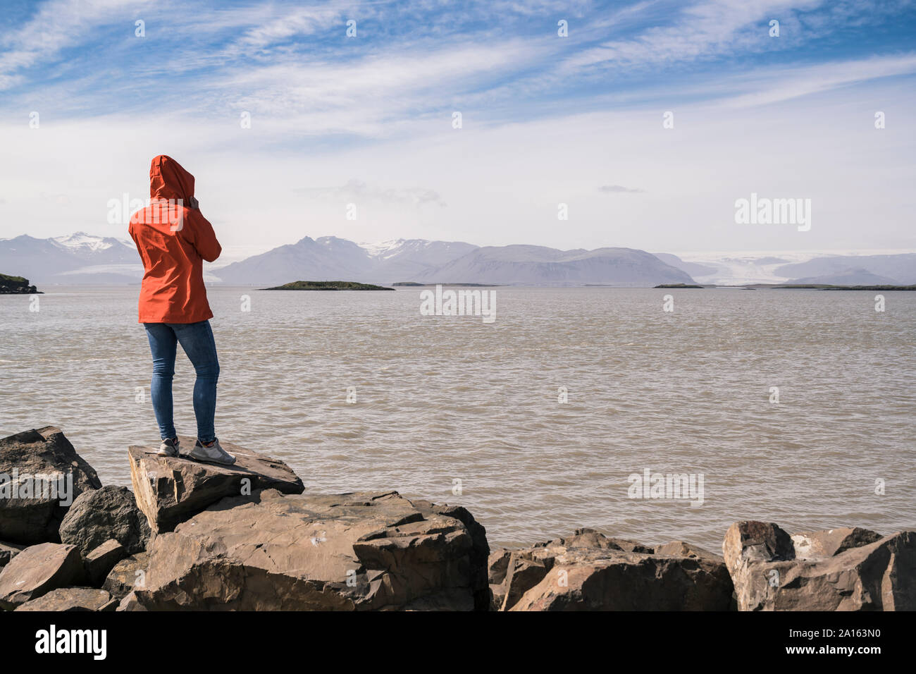 Giovane donna che lo standig massi, guardando il mare a sud est dell'Islanda Foto Stock