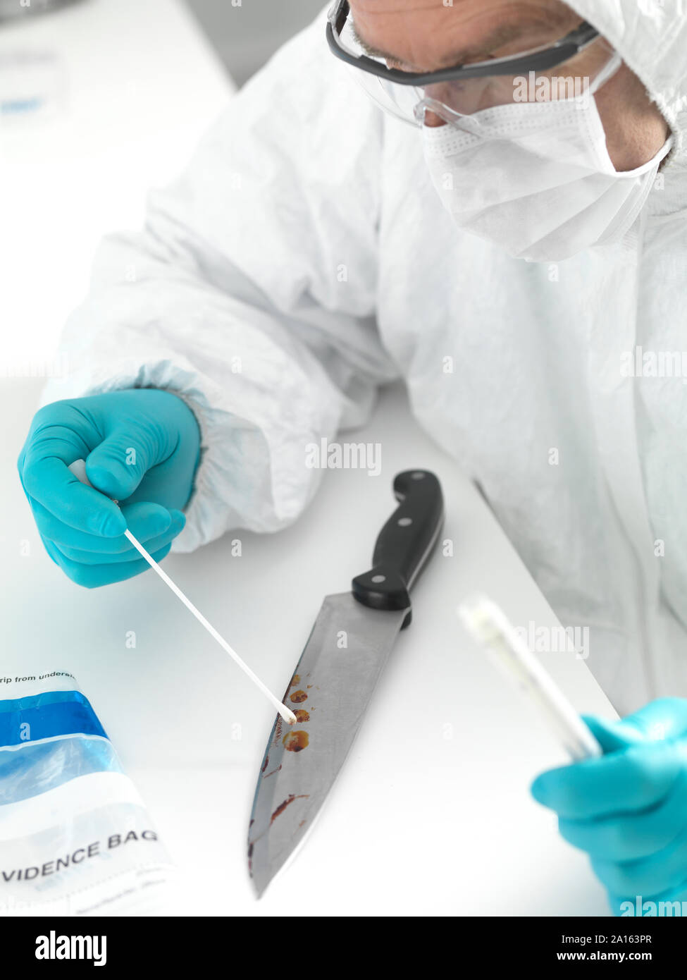 Lo scienziato forense assunzione di prove del DNA da sangue cosparse il coltello Foto Stock