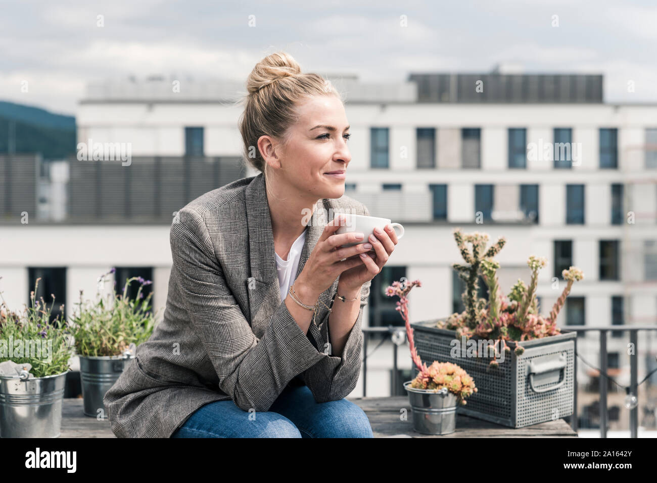 Imprenditrice con tazza di caffè seduti sulla terrazza sul tetto avente una pausa Foto Stock
