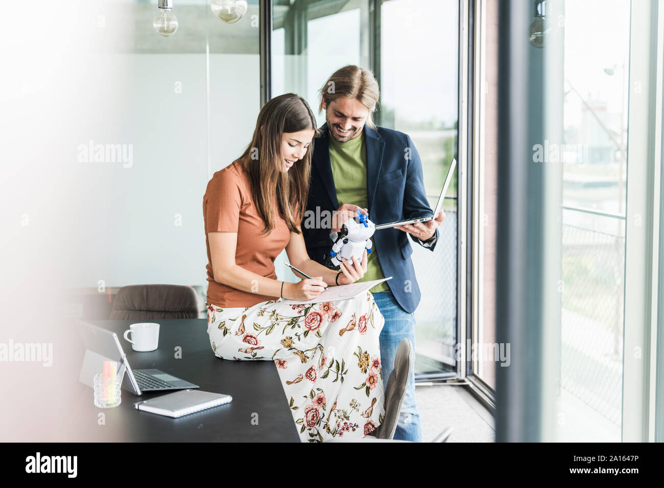 Giovane imprenditrice e imprenditore lavora su robot in ufficio Foto Stock