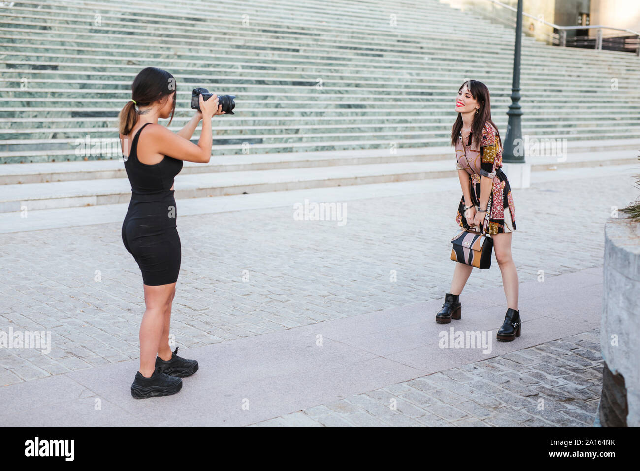 Giovane donna che indossa abiti modellato in posa per una fotografia di sparare su scale Foto Stock