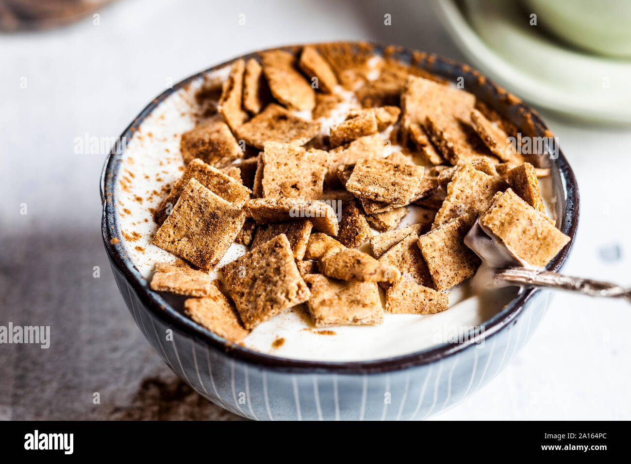 Close-up di fresco cotto in casa cannella cereali con aggiunta di yogurt in un recipiente Foto Stock