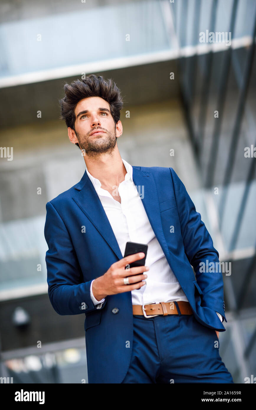 Imprenditore con un telefono cellulare al di fuori di un edificio per uffici Foto Stock