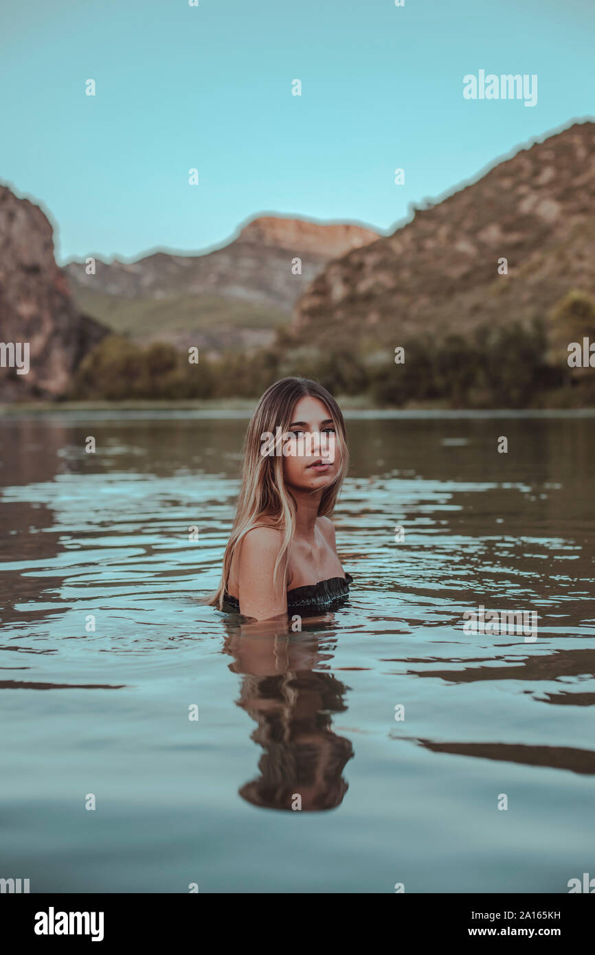 Giovane donna bionda di balneazione in un lago in estate di sera Foto Stock