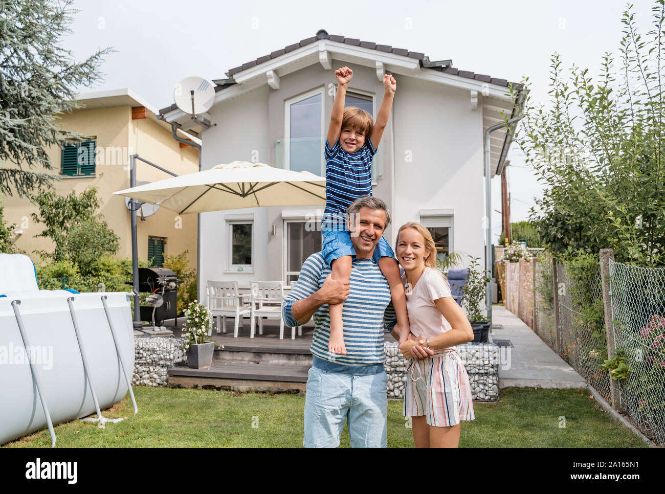 Ritratto di padre con moglie figlio che porta sulle spalle in giardino Foto Stock