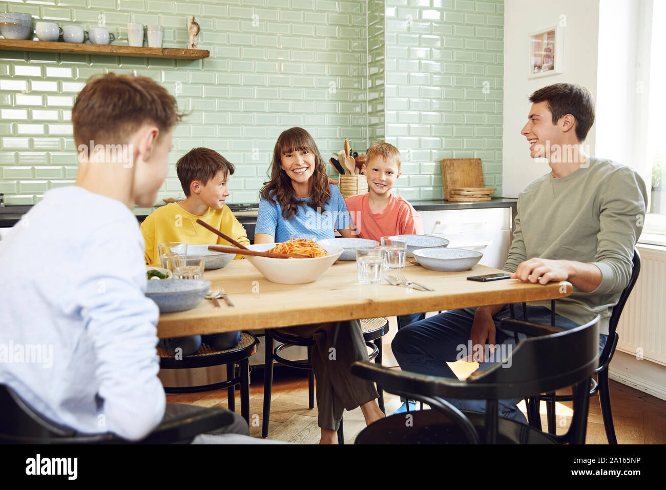 Madre mangiare spaghetti con i suoi figli in cucina Foto Stock