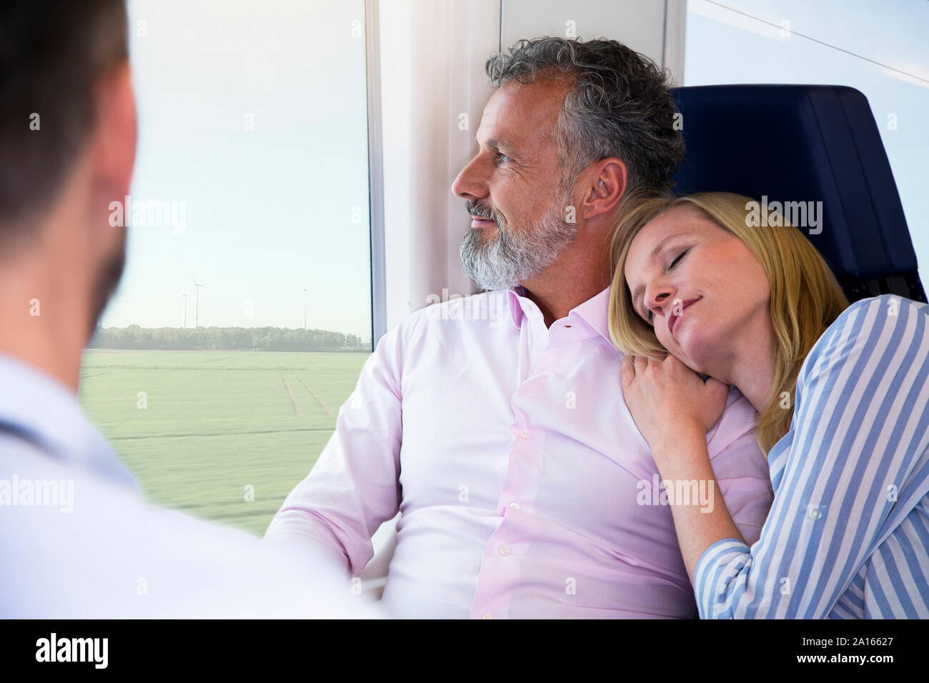 Coppia che viaggia in treno, donna appoggiata su uomini della spalla Foto Stock