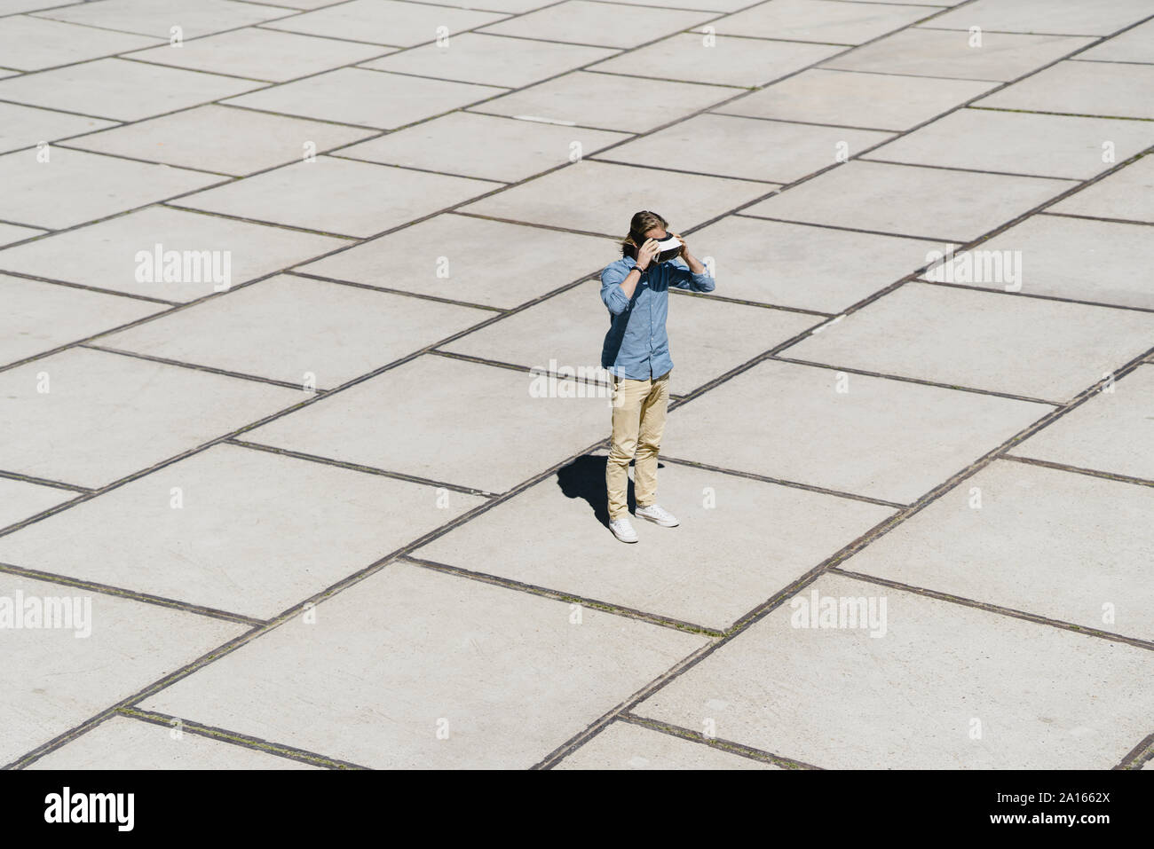 Giovane Uomo con occhiali VR in piedi su un quadrato Foto Stock