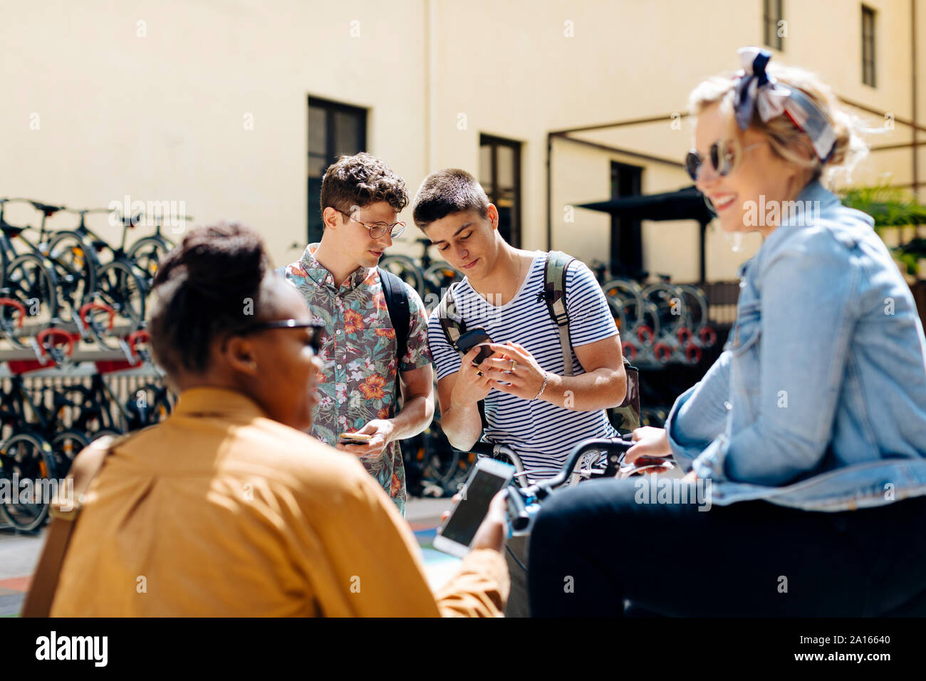 Gli studenti riuniti in un cortile, parlando, smartphone unsing Foto Stock