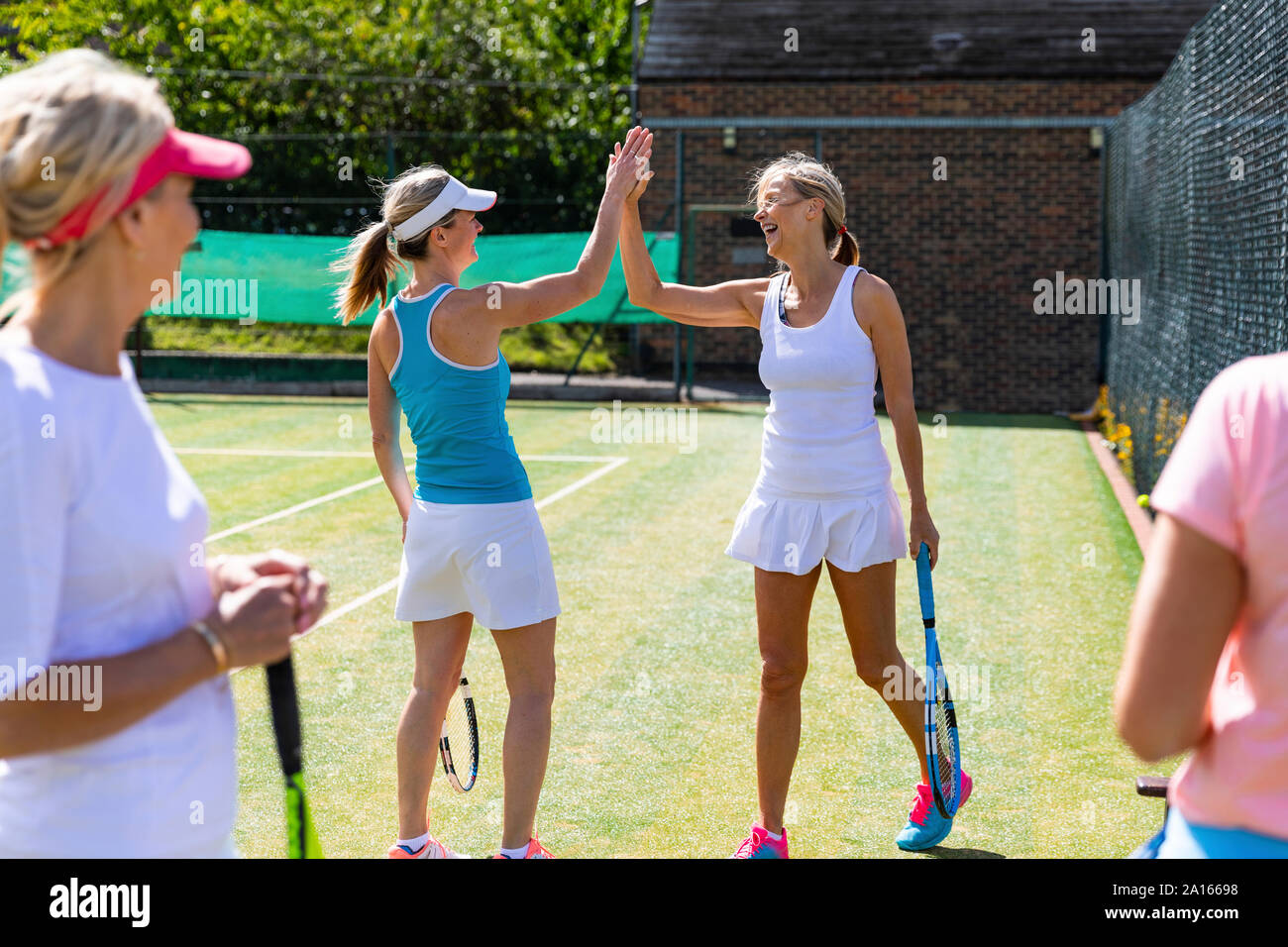 Felici donne mature celebrando dopo il match di tennis Foto Stock