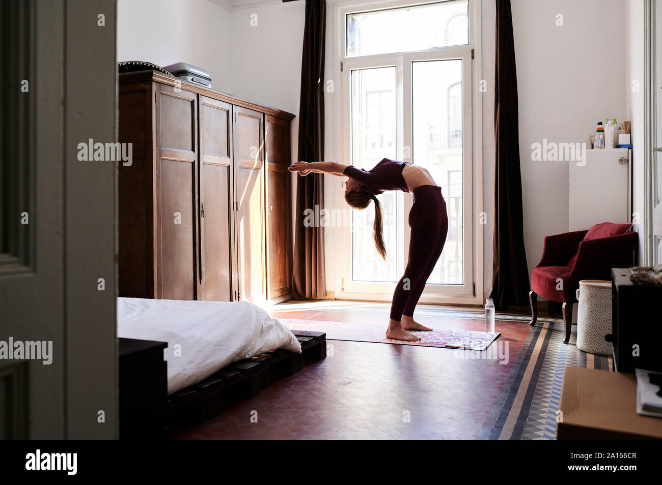 Bruna giovane donna a praticare yoga in dormitorio studenti Foto Stock