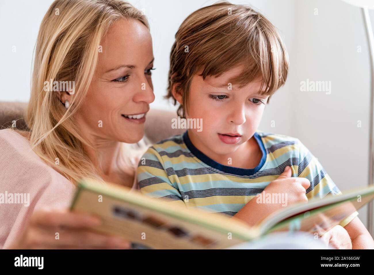 Madre e Figlio la lettura di un libro insieme sul lettino a casa Foto Stock