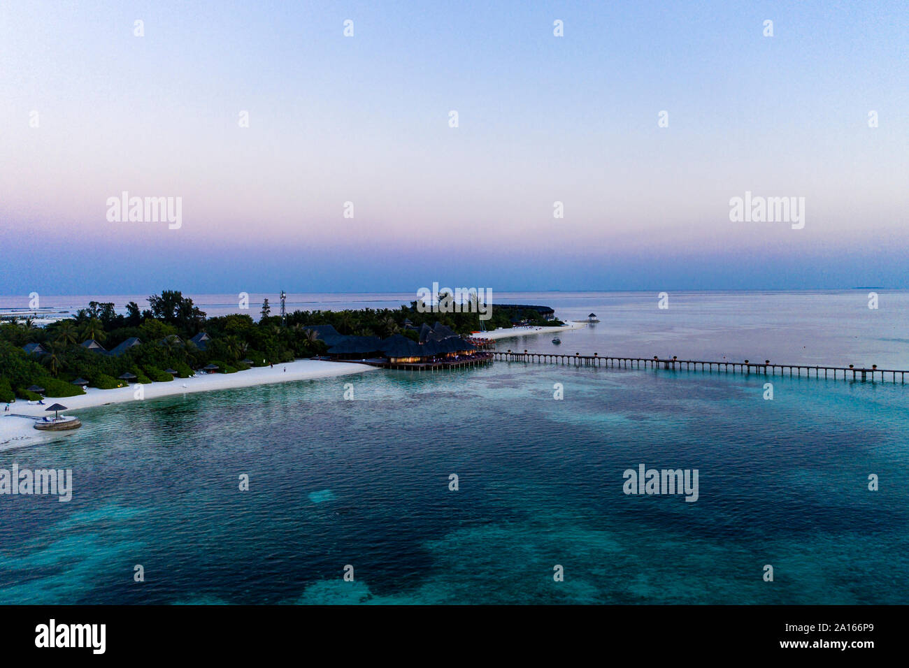 Maldive Olhuveli island, Pier e resort a South Male Atoll laguna al tramonto Foto Stock
