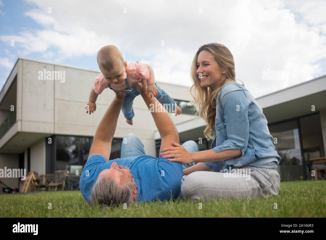 Padre Felice con la madre solleva Baby girl in giardino Foto Stock