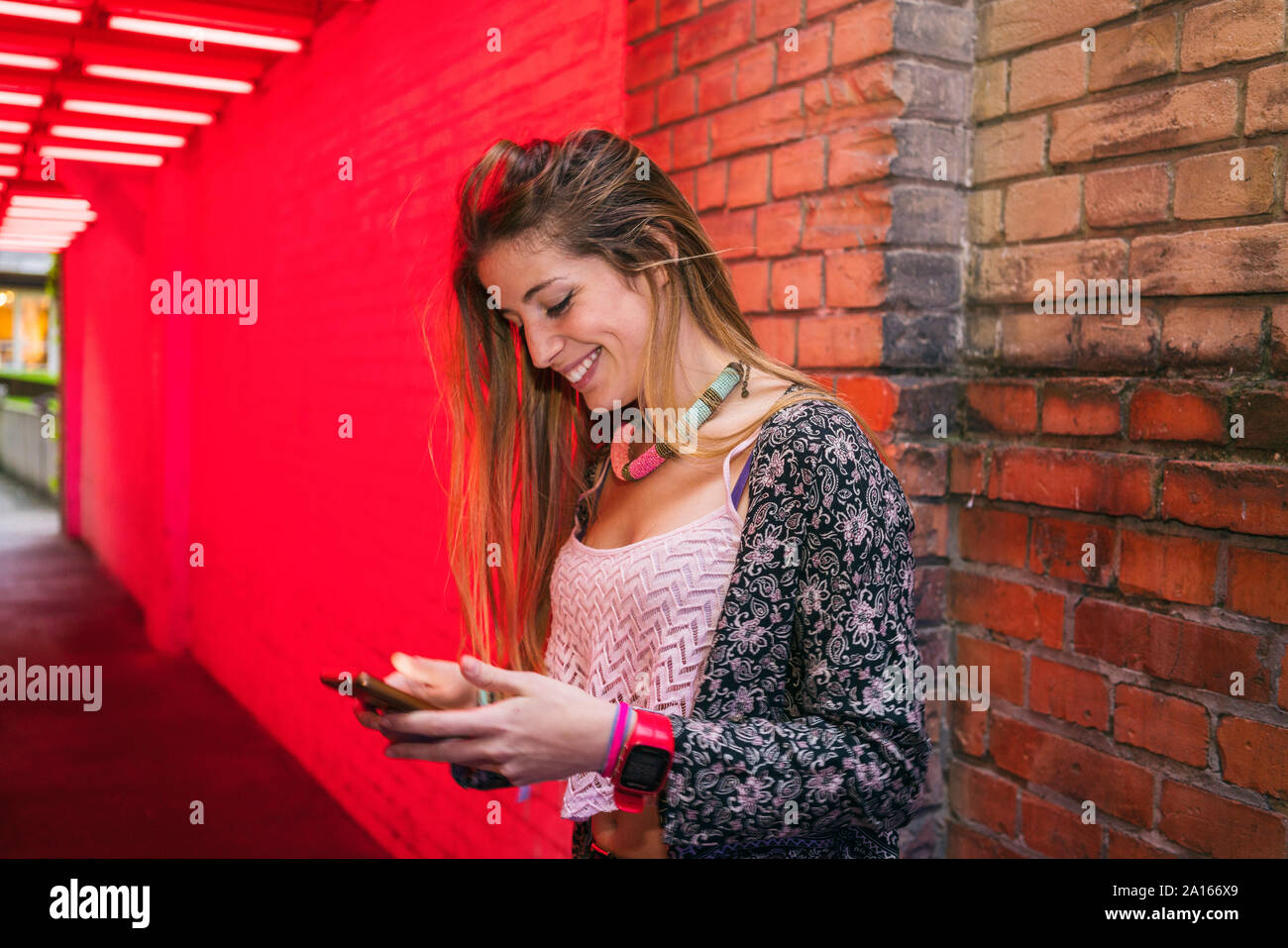 Felice giovane donna utilizzando il cellulare in città Foto Stock