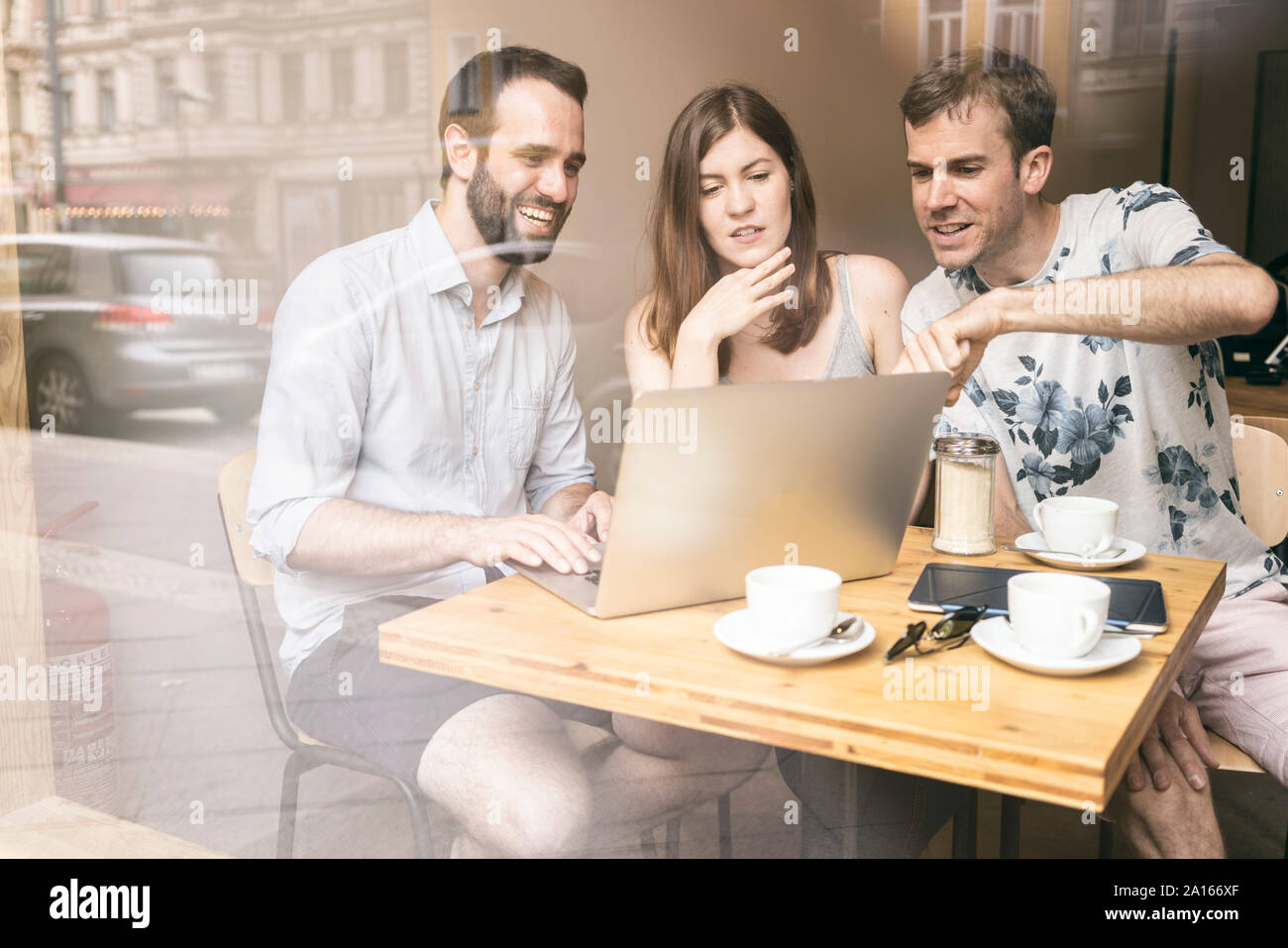 Gruppo di amici seduti insieme in un cafe con il computer portatile Foto Stock