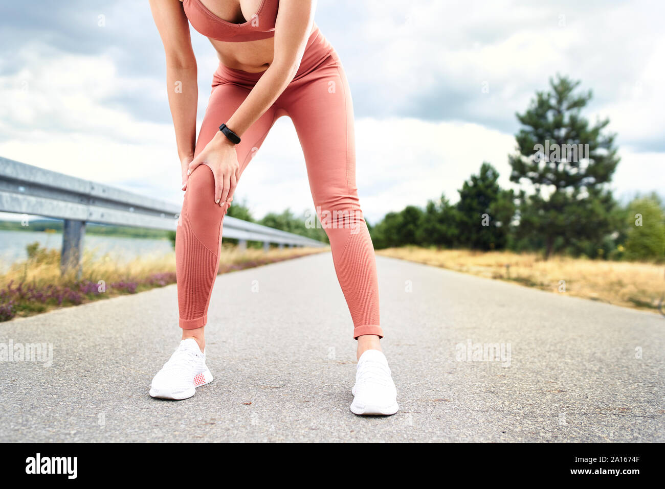 Donna che mantiene il ginocchio dolorante durante l'allenamento all'aperto Foto Stock