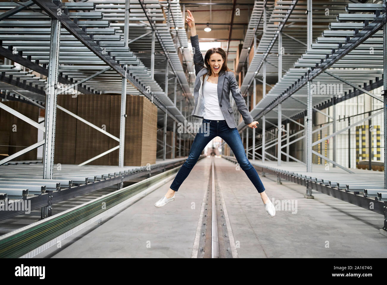 Emozionato imprenditrice jumping in fabbrica Foto Stock