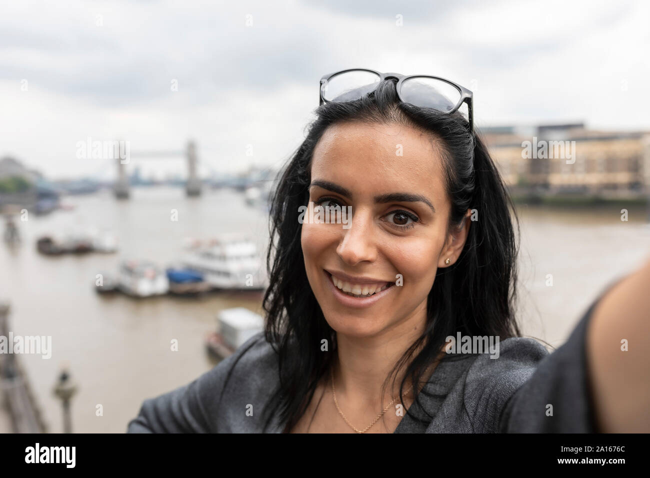 Ritratto di awoman prendendo un selfie nella città con il Tower Bridge sullo sfondo, London, Regno Unito Foto Stock