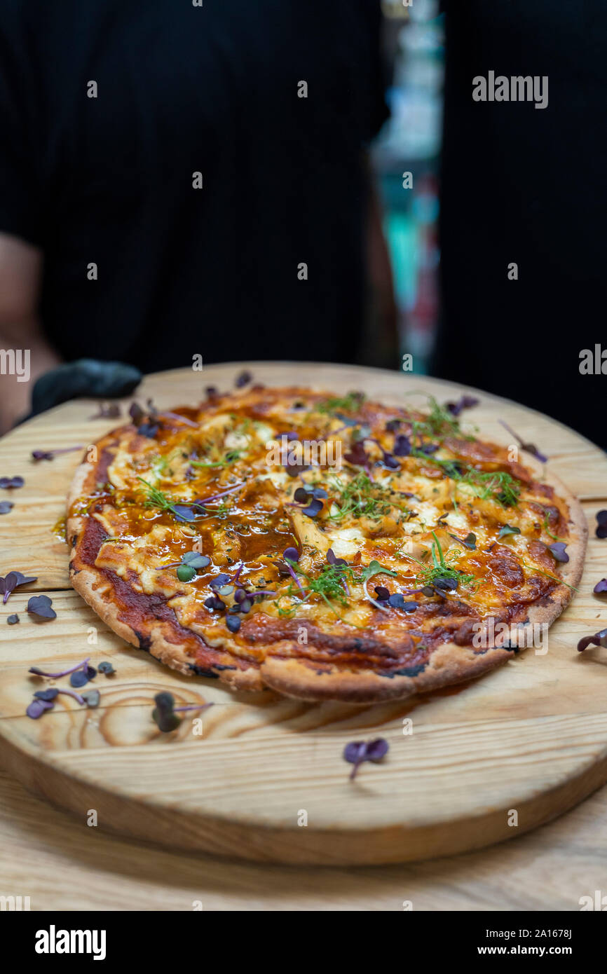 Sezione mediana di attendere il personale azienda pizza fresca su legno scheda di servizio nel ristorante Foto Stock