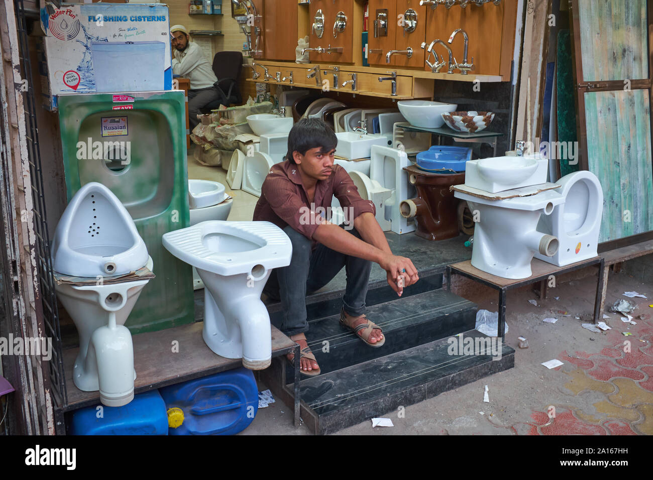 Un assistente in un negozio per impianti sanitari e le utility di uso domestico in Mumbai, India, seduti tra gabinetti e orinatoi in vendita Foto Stock