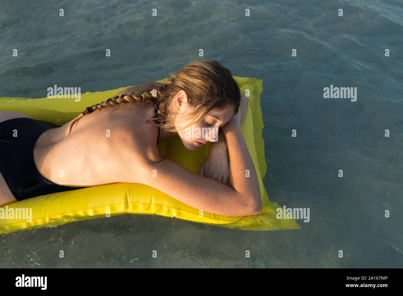 Giovane donna sdraiata su giallo airbed e dormire Foto Stock