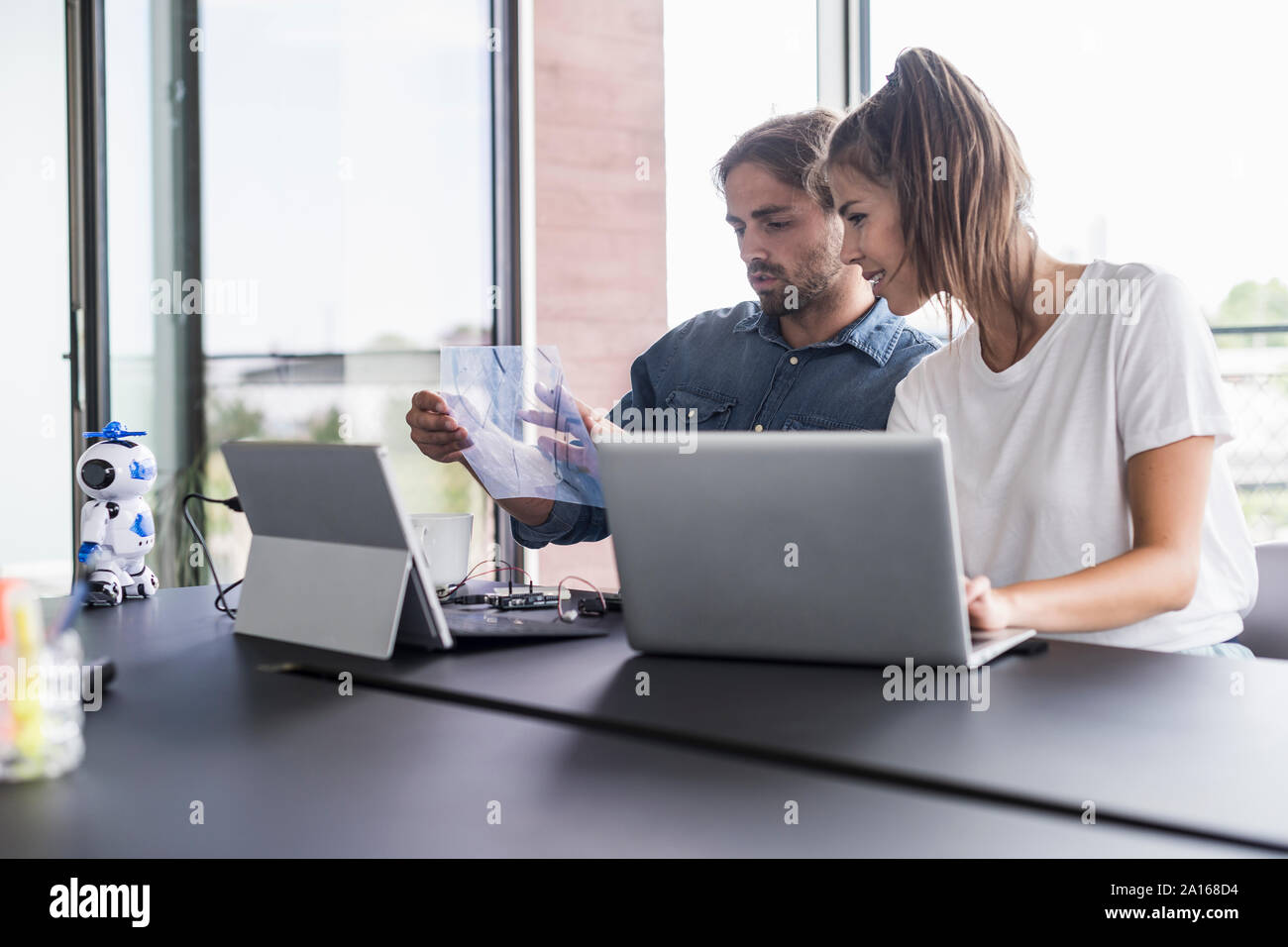 Giovane uomo e donna che lavorano insieme alla scrivania in ufficio Foto Stock