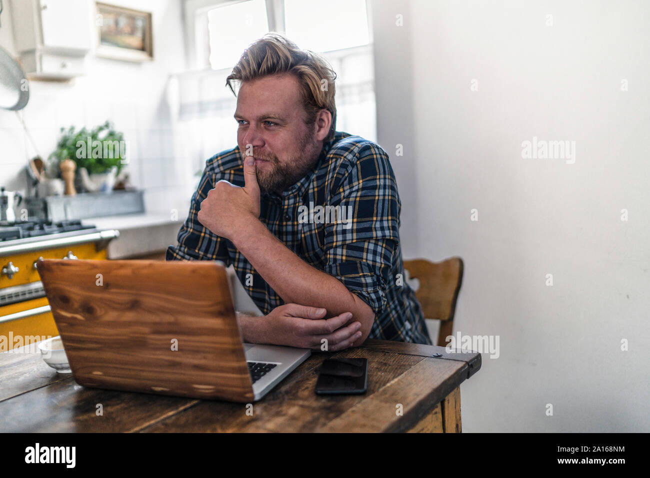 Uomo che utilizza sul computer portatile sul tavolo da cucina Foto Stock