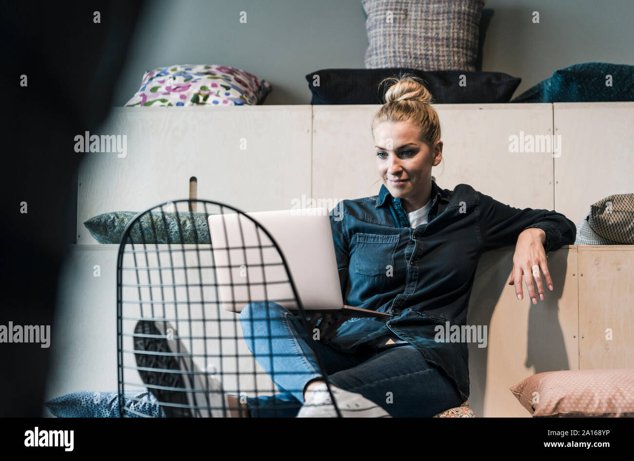 Sorridente casual imprenditrice utilizzando computer portatile in ufficio lounge Foto Stock